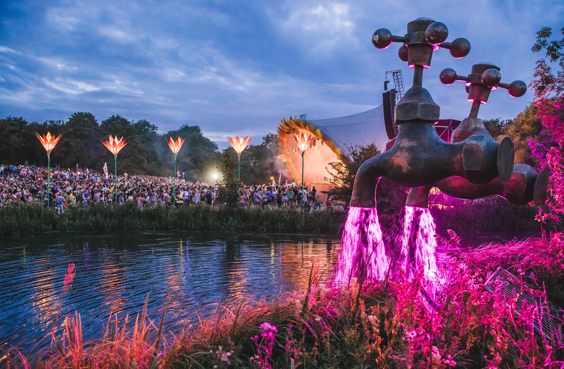 secret garden main stage across from a river with fake faucets with pink water running into the lake