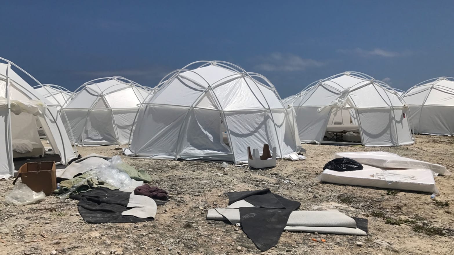 budget tents on a pebbly beach with bare mattress pulled out tents